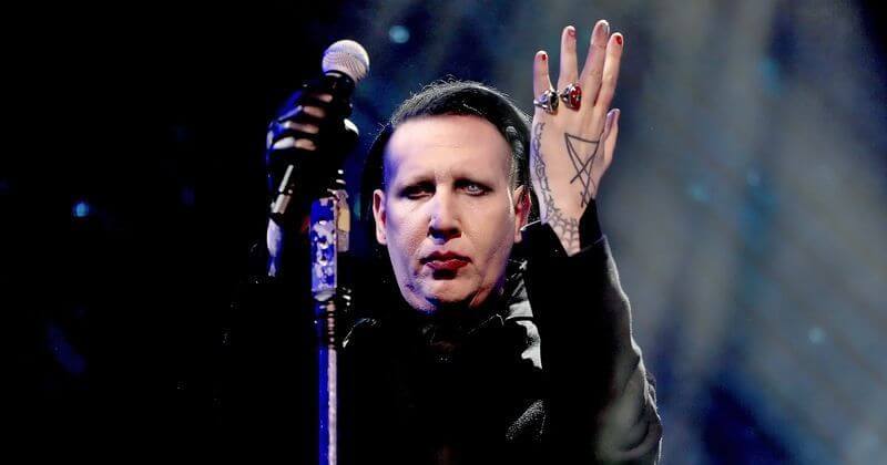 Marilyn Manson di atas panggung memegang mikrofon sambil mengangkat tangannya